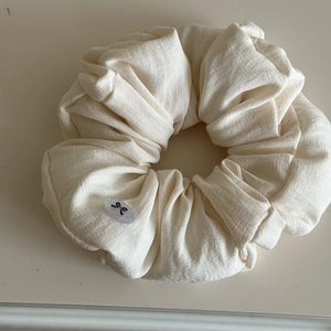 Close-up of cream soft fabric scrunchie featuring a translucent resin bow ornament