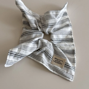 Detail of pinstripe fabric scrunchie with a beige letter patch and soft cotton texture