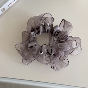 Detailstruktur aus grauem Satin und Organza-Haargummi mit mehrlagigem Falten-Design