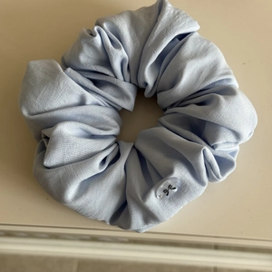 Detail of light blue pleated puffy scrunchie featuring a clear acrylic bow charm