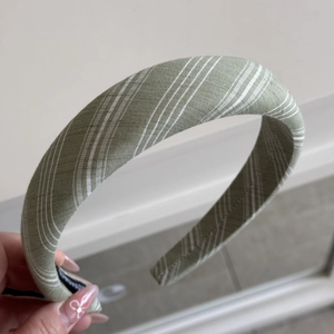 Close-up of a green striped fabric headband with a non-slip lining and soft texture