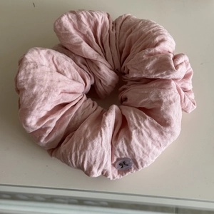 Detail of pink ruffled fabric scrunchie with a decorative purple bow button