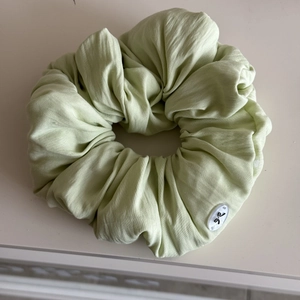 Macro shot of light green ruffled hair scrunchie with oval butterfly logo detail