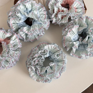 Close-up of five plaid hair scrunchies with pink and blue lace edges on a tray