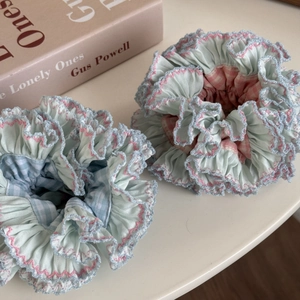 Detail of mint green hair scrunchies with pink scalloped edges and checkered fabric textures