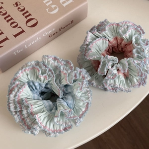 Close-up of ruffled blue and pink plaid hair scrunchies with delicate embroidered edges
