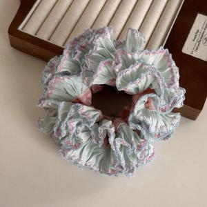 Close-up of light blue pleated fabric hair scrunchie with pink floral patterns and lace trim