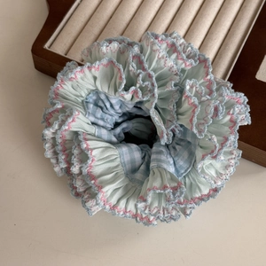 Detail of blue plaid scrunchie featuring pink wave stitching and delicate lace edges