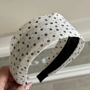 Macro shot of wide headband with black floral print on wrinkled white fabric texture