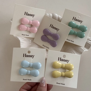 Detailed set of mini bow hair clips in vibrant pastel colors on a shell display