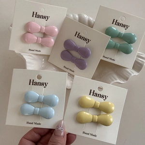 Mini macaron colored bow hair clips in pink and blue on a display card