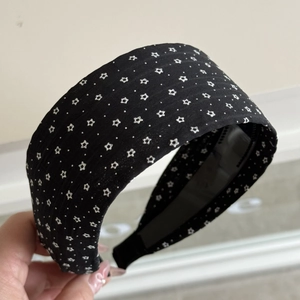 Close-up of wide fabric headband with black white polka dots and anti-slip inner strip