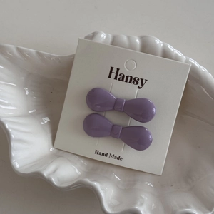Detail showing two purple mini bow hair clips on a white handmade display card