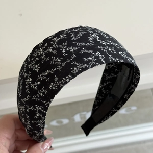 Close-up of wide headband featuring classic black fabric with white floral pattern
