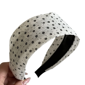 Wide white headband with black stars and dots pattern featuring a non-slip black lining