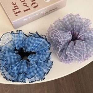 Detail of blue plaid and lavender mesh scrunchies with wavy edges on a desk