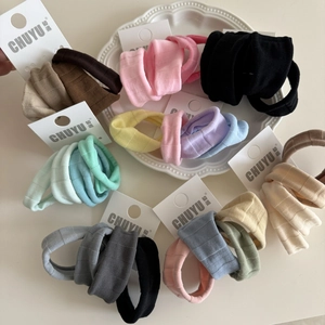 Détail de chouchous en maille côtelée multicolores présentés sur une assiette blanche