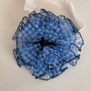 Detailed close-up of a blue and white plaid mesh scrunchie with embroidered wavy edges