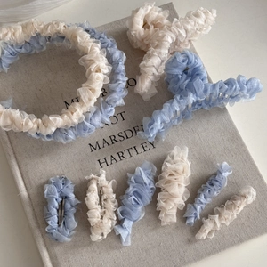 Gros plan d'accessoires de cheveux en maille plissée bleue et beige sur un livre