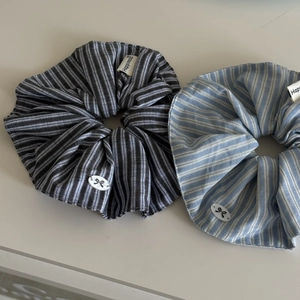 Close-up of blue striped fabric scrunchies with Happiness label and bow detail