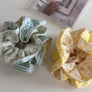 Dettaglio di elastici scrunchie a quadretti verdi e gialli con fiori su fondo bianco