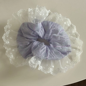 Detail der lila Netzschicht und elegante weiße Spitzenstickerei auf dem Haargummi
