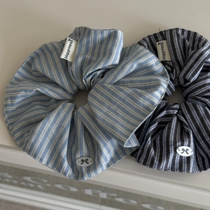 Close-up of blue striped scrunchies with Happiness label and bow charm detail