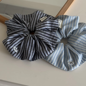 Close-up of blue striped scrunchies with Happiness label and bow detail on desk