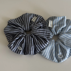 Detailed close-up of blue and black striped scrunchies set with Happiness cloth label