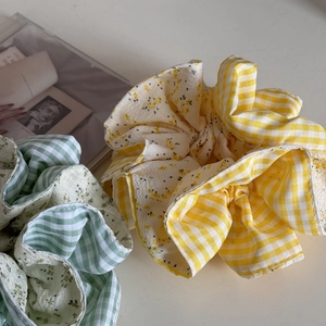Dettaglio di elastici scrunchies a quadretti e fiori gialli e verdi in cotone