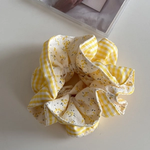 Dettaglio dell'elastico per capelli a quadretti gialli con fiori e trama in cotone