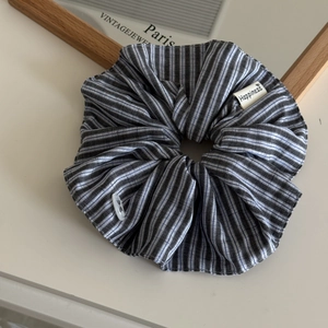 Close-up of blue striped scrunchie with Happiness label and delicate button detail