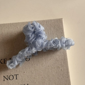 Gros plan d'une pince à cheveux en tulle plissé bleu clair avec texture de tissu délicat