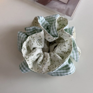 Dettaglio di uno scrunchie in stile coreano con motivo a quadretti verdi e fiori