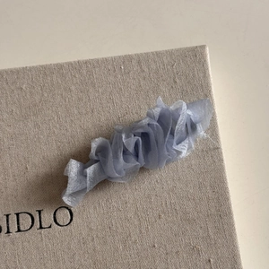 Détail de la pince à cheveux en tulle bleu montrant la texture plissée et le tissu élégant