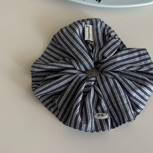 Detailed macro view of blue striped oversized scrunchie with Happiness woven label