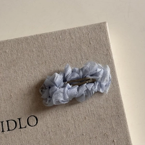 Vue détaillée d'une pince à cheveux en tulle plissé bleu avec base métallique argentée