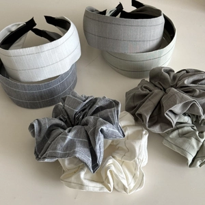 Flat lay of striped fabric headbands and scrunchies set in grey and sage green tones