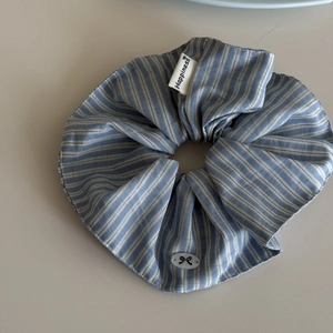 Detail of blue striped scrunchie with Happiness label and black bow ornament