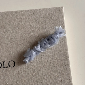 Détail du tissu en maille plissée bleu clair sur la jolie pince à cheveux à bec de canard