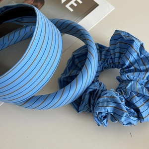 Detailed set of blue striped cotton headbands and a soft scrunchie on white background