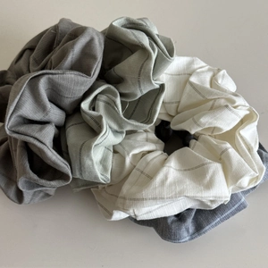 Detailed view of three striped cotton linen scrunchies in grey, green, and beige