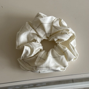 Detailed close-up of cream-colored scrunchie with grey horizontal stripes and fabric texture