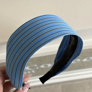 Detail of light blue striped headband featuring non-slip teeth and black end caps