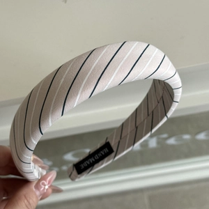 Close-up of pink beige striped headband with black handmade label and non-slip inner lining