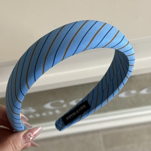 Close-up of handmade wide padded headband with sky blue stripes and hand made label