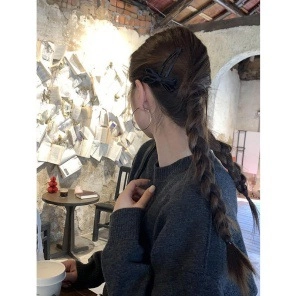 Side view of large black ribbon hair clip on woman head in retro cafe setting