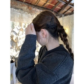 Close-up of black ribbon bow hair clip and silver hoop earrings on a female model