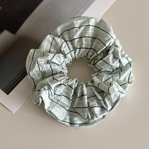 Detailed view of oversized mint green striped cotton scrunchie with soft ruffled texture