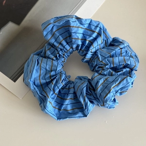 Detail showing high-count cotton blue striped scrunchie with soft pleated texture